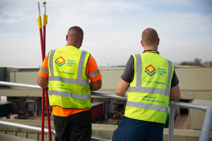 two employees in hi-vis on a roof