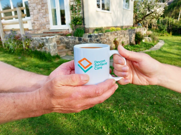 two hands exchanging a mug of tea