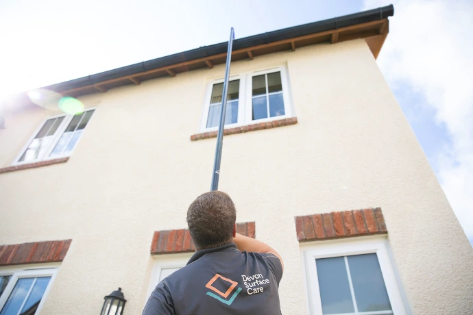 using a long pole to hoover out a gutter