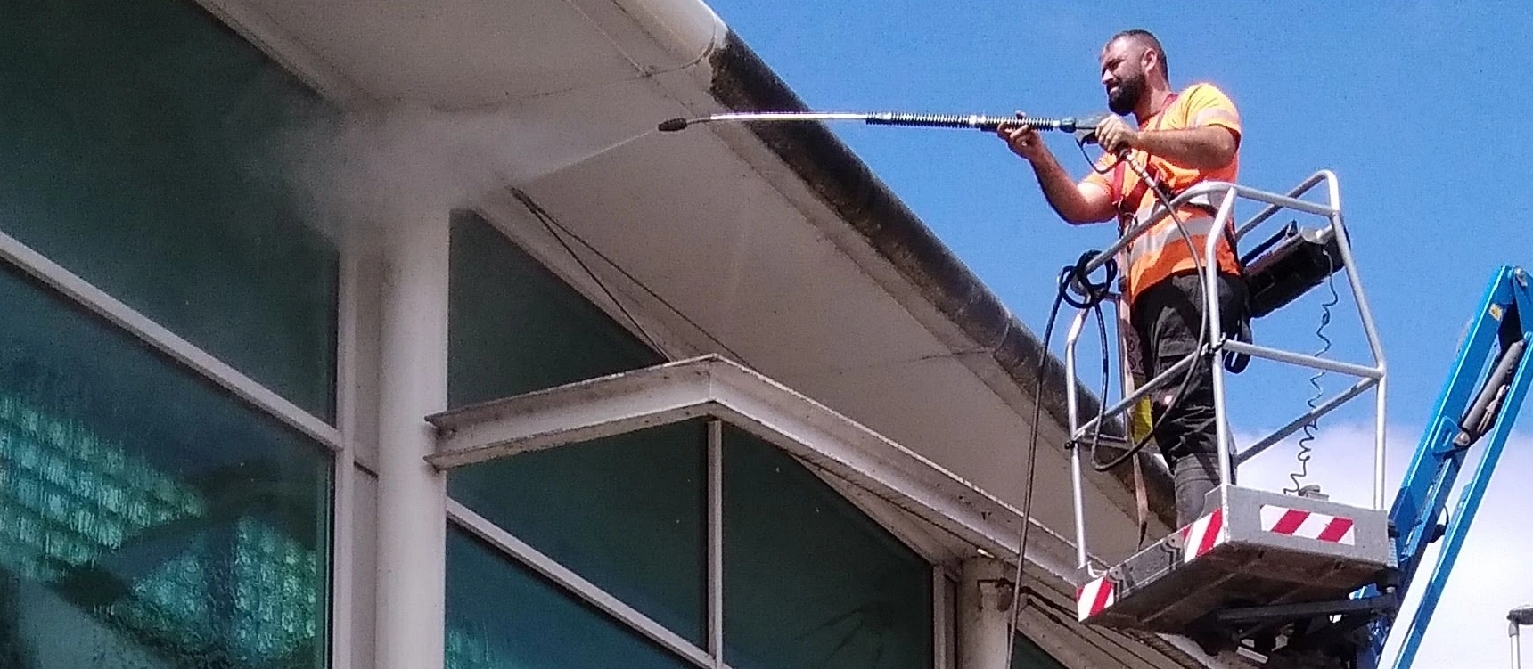 a man jet washing a facade on a commercial building