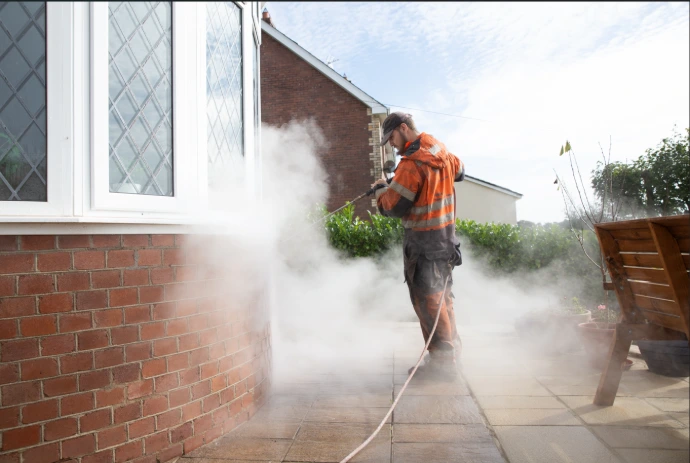 a man steam cleaning a brick wall